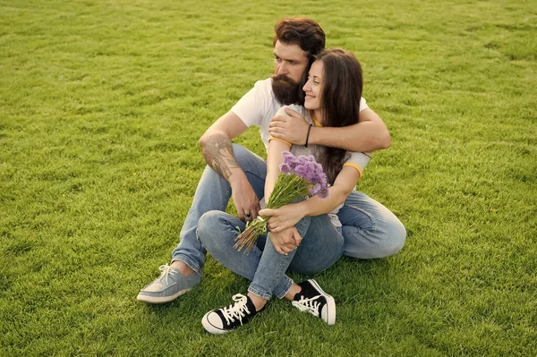 Romantikus kiruccanás. A szerelmesek a zöld fűben pihennek. A szexi nő és a szakállas férfi élvezik a nyári napot. Romantikus szerelem. Romantikus társkereső kapcsolat. Romantikus nyaralás. Szerelem és romantika — Stock Fotó