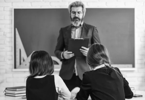 Heel druk. terug naar school. Leraar en leerlingen werken samen aan een bureau op de basisschool. creativiteit openbaar te maken en te ontwikkelen. Docent werkt met creatieve kinderen. kleine meisjes kinderen op school — Stockfoto