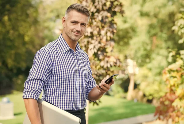 Negocios ágiles. comunicación con dispositivos modernos. permanezca siempre en línea. hombre alegre hablar por teléfono móvil. Hombre de negocios guapo ha arreglado el pelo canoso. chico maduro llevar ordenador — Foto de Stock