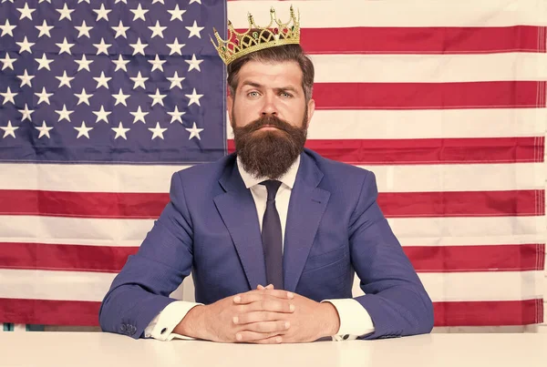 Αξιόπιστος επιχειρηματίας όμορφος άντρας κάθεται γραφείο αμερικανική σημαία φόντο, έννοια αμερικανικό όνειρο — Φωτογραφία Αρχείου