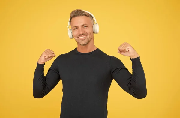 Przystojny szczęśliwy człowiek słuchać muzyki w stylowe słuchawki na żółtym tle, nowoczesna technologia — Zdjęcie stockowe