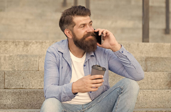 Hi dear. Modern urban life. Bearded man phone conversation. Mobile conversation. Personal communication. Calling friend. Pleasant conversation. Real connect. Drink coffee while talking. Glad to hear