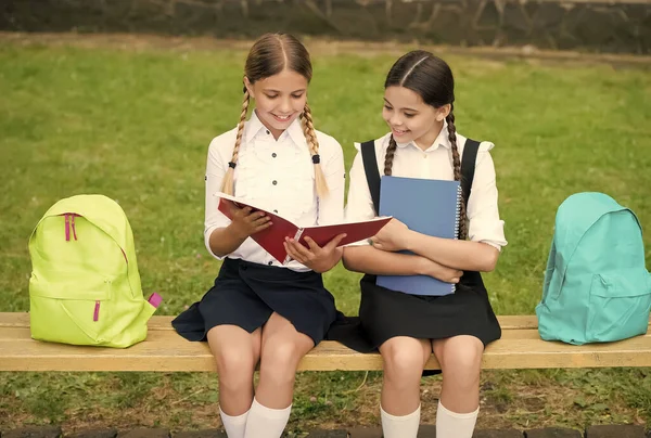 Ajuda e apoio. as crianças lêem caderno para fazer anotações. infância feliz. de volta à escola. alunos adolescentes prontos para a aula. Preparar para o exame. estudar juntos ao ar livre. meninas pequenas com livros e mochilas — Fotografia de Stock