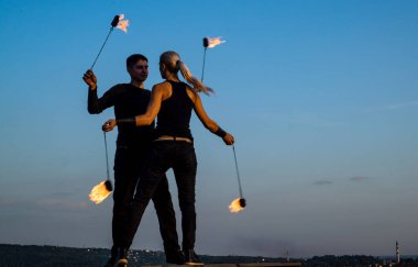 Harmony of rhythm and movement. Couple of dancers with poi on blue sky. Fire dance.