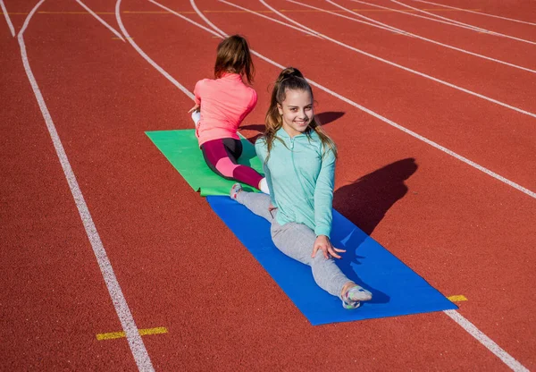 Happy fit girls do splits on stretch mat on athletics track, pilates — Foto de Stock