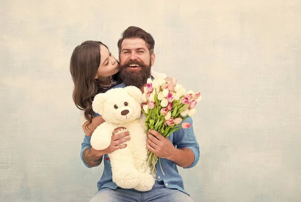 Счастливая семья отца и дочери обнимаются с весенним цветочным букетом тюльпанов и игрушкой плюшевого медведя, День отца — стоковое фото