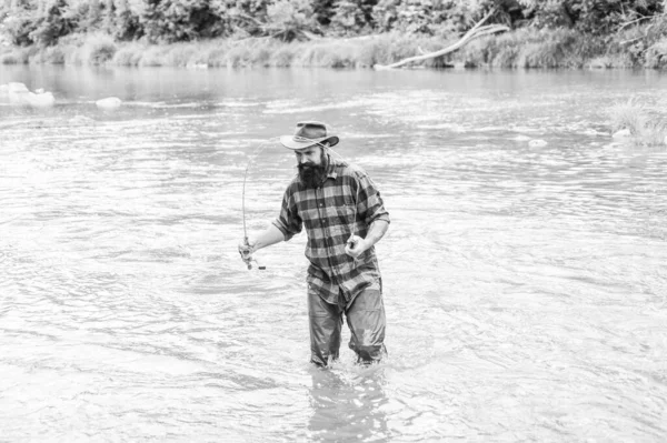 Fisher masculine hobby. Fishing requires to be mindful and fully present in moment. Fisher fishing equipment. Rest and recreation. Fish on hook. Brutal man stand in river water. Man bearded fisher