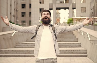 Enerji konsepti. Neşe ve olumluluk. Modern hayat. Şehir merkezinde yürüyen kulaklıklı bir adam. Müzik dinliyordum. Sırt çantalı yakışıklı hippi. İyi ses. İşe gidiş yolu. Müzikle baş başa. Özgür ve mutlu