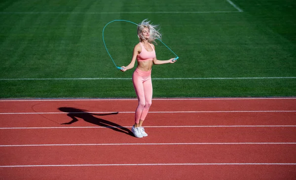 Athlète femme énergique sautant sur corde sauter échauffement sur le stade faire de l'entraînement sportif, athlétisme. — Photo