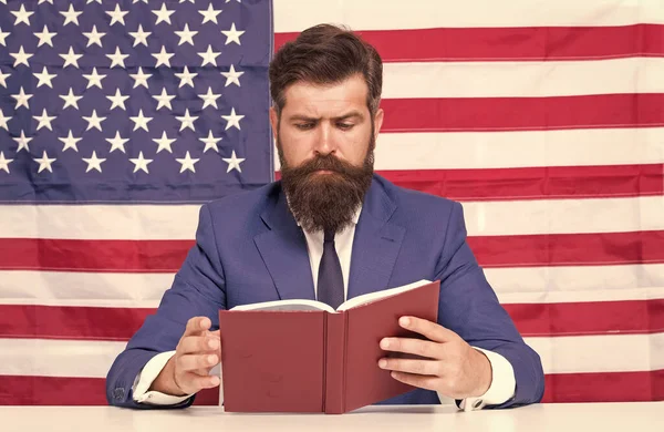 Hipster homem leitura livro EUA bandeira fundo, professor universitário conceito — Fotografia de Stock