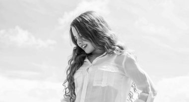 Mükemmel bir kadın. Çocuk modası. Doğal dişi güzellik. Mutlu çocukluk. Gökyüzü arka planında sevimli bir çocuk. Kuaför salonu. Yaz modasına uygun bir görünüş. Uzun kıvırcık saçlı güzel genç kız.