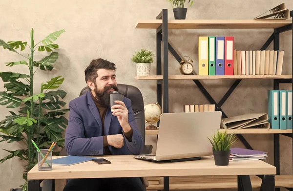 Счастливый хипстер в формальной одежде пьет кофе за рабочим столом менеджеров в современном рабочем кабинете — стоковое фото