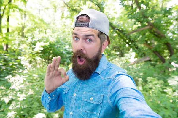 Zaskoczony człowiek robiący selfie. szczęśliwy brodaty mężczyzna z ok gestem. brutalny hipster — Zdjęcie stockowe