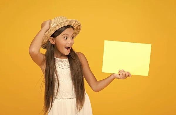 Tropisch elegantes Mädchen mit leerem Papier. Kopierraum. glückliches Mädchen mit Strohhut auf gelbem Hintergrund. Accessoires der romantischen Reisenden. Retro-Kids äußern sich überrascht. Ankündigung und Informationen — Stockfoto