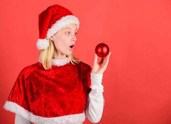 Lieblingszeit Weihnachten. Weihnachtsspaß. Mädchen glücklich tragen Weihnachtsmann Kostüm feiern Weihnachten halten Ball Dekor roten Hintergrund. Genießen Sie feiern ein frohes neues Jahr. Konzept zur Weihnachtsvorbereitung — Stockfoto