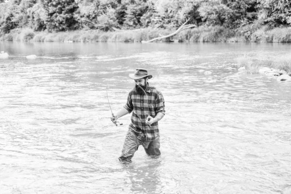 Pasatiempo masculino Fisher. Pescado en gancho. Hombre brutal parado en el agua del río. Hombre barbudo pescador. La pesca requiere ser consciente y estar plenamente presente en el momento. Equipo de pesca Fisher. Descanso y recreación —  Fotos de Stock