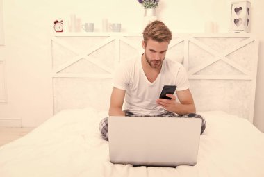 COVID-19 pandemik karantina sırasında iletişim. Adam yatakta cep telefonu kullanıyor. Mobil bağlantı
