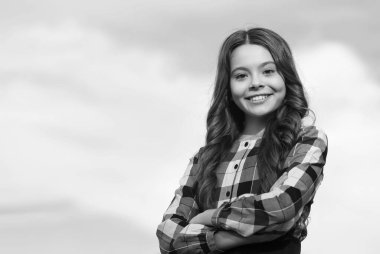 Okula geri dönen mutlu küçük bir çocuk. Uzun dalgalı saçları var. Arka planda gülüyor, kuaförlük yapıyor, fotokopi çekiyor.