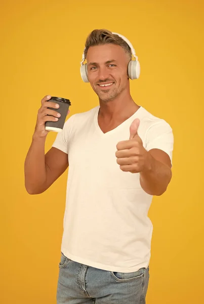 Bästa delen av morgonen. Glad man ger tummen upp till kaffet. Godkännande gest. Kafé och hämtmat. Musikteknik. Modern livsstil. Tillfällig stil. Varje morgon ska vara inspirerande — Stockfoto