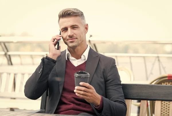 Hablando de negocios con una taza de café. Un hombre guapo tiene conversación telefónica. Comunicación empresarial. Conversación móvil. Descanso. La vida moderna. Nuevas tecnologías — Foto de Stock