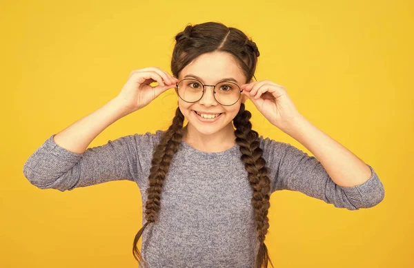 Miúda inteligente. Aluno da escola menina usar óculos fundo amarelo. Que nerd adorável. Conceito de estudante. Menina inteligente visão ruim. Deixa-me ver. A ler melhor com óculos. Óculos de saúde de olhos — Fotografia de Stock