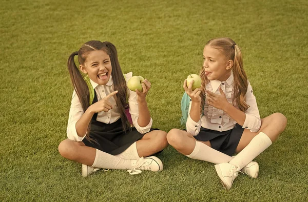 Tener sabor a limón. Niña apuntando a fruta agria de manzana. Ácido de fruta. Los niños pequeños comen fruta sobre hierba verde. Aperitivo escolar. Fruta orgánica de vitaminas. Comida saludable. Salud escolar y nutrición —  Fotos de Stock