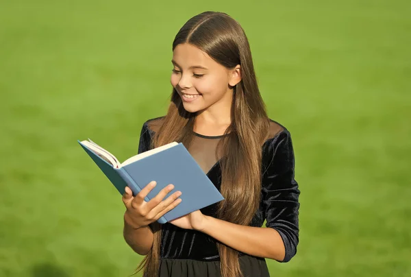 Nakrm mysl. Šťastné dítě čte knihu v knihovně. Roztomilý knihomol studuje trávu. Školní knihovna. Vzdělání ve čtení a gramotnosti. Bibliotheca. Lekce literatury. Ukojit žízeň poznání — Stock fotografie