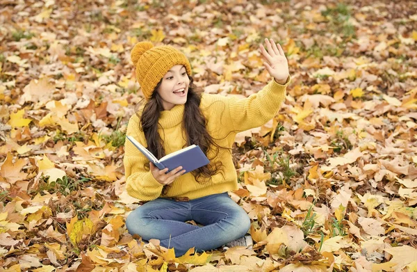 Hola escuela. Niño feliz dar saludo libro de lectura en las hojas de otoño. Biblioteca escolar. Educación de alfabetización. Día del conocimiento. 1 de septiembre. Temporada de otoño — Foto de Stock