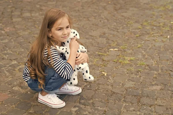 Brincadeira de criança pequena bonito com cão de brinquedo sentado no pavimento de seixos ao ar livre, jogando, espaço de cópia — Fotografia de Stock