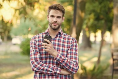 Elinde kahve ile birlikte kağıt bardak tutan yakışıklı bir adam. Sabah kahvesi içen adam. Her havada sıcak çay. Günaydın içecekler. Kendine güvenen iş adamı