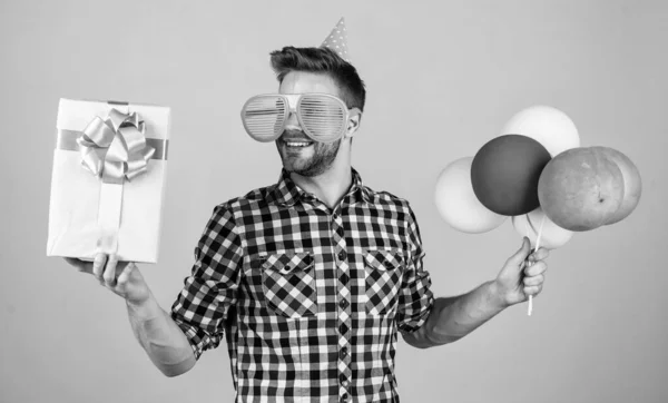 Alles Gute zum Geburtstag. Männerweihnachtsfeier. bärtiger Typ mit Party-Luftballons und Geschenkbox. Der unrasierte, gutaussehende Mann mit der Borste feiert geschäftlichen Erfolg. Ausdruck puren Glücks — Stockfoto