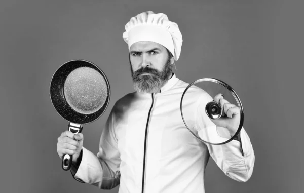 Bakproces. Een man met een baard houdt een koekenpan vast. Koken in de pot. voor het bereiden van voedsel. Een man met baard kookt in de keuken. culinair en keuken. Keukengerei. - Ja. Gezond eten koken. kokend smakelijk gerecht — Stockfoto