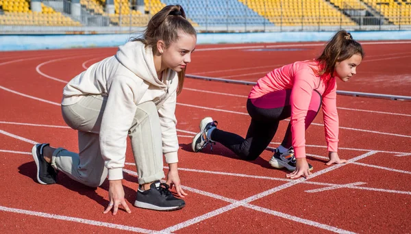 Ajuste corredores adolescentes se ponen en posición lista en pista de atletismo, empezar — Foto de Stock