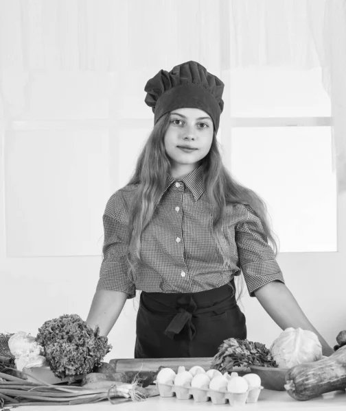 Sourire adolescent fille dans chef uniforme cuisine légumes, végétarien — Photo