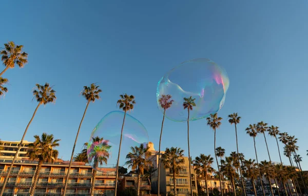 As bolhas de sabão voam acima da cidade tropical. Bolhas gigantes no céu azul. Bolhas de sabão iridescentes — Fotografia de Stock