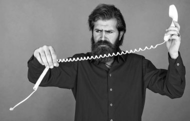 Kırıldı. Telefonla konuşan acımasız bir adam. İletişim. Sakallı adam kırmızı gömlek giyer. Sıradan bir erkek telefonu. Sohbet konsepti. adam sekreter ya da asistan retro telefonda konuşuyor