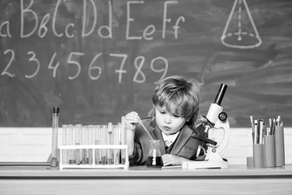 テクノロジーと科学の概念。子供は学校で生物学と化学を勉強する。学校教育。生物分子を探索する。幼児の天才赤ちゃん。学校の教室で顕微鏡や試験管の近くの男の子 — ストック写真