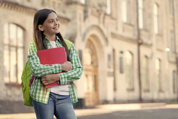 Glückliches Kind mit nachdenklichem Blick halten Bücher und Schultasche im Freien, Schulbildung, Kopierraum — Stockfoto