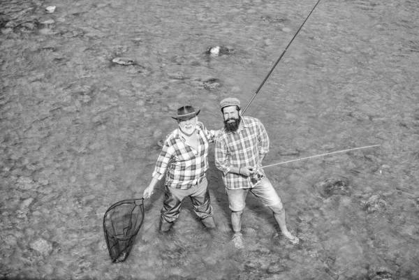 Pracować razem. Letni weekend. dojrzali mężczyźni wędkarze. męska przyjaźń. nawiązywanie więzi rodzinnych. ojciec i syn łowią ryby. hobby i aktywność sportowa. Przynęta na pstrągi. dwóch szczęśliwych rybaków z wędką i siecią — Zdjęcie stockowe