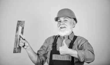 Sıva için alçı aletleri. sarı alçıpanlı alçıpanlı alçıpan spatulası. Üniformalı sıvacı, duvarları kapalı bir yerde sıva yapıyor. Spatulalı adam. Macun katmanının uygulanma süreci