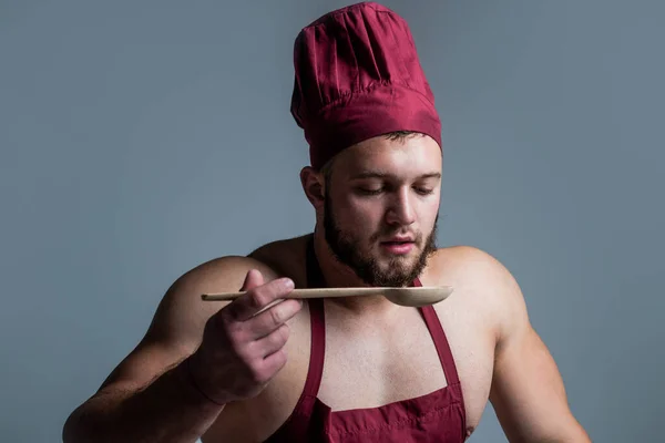 Спортивный парень с сильными мышцами в фартуке шеф-повара приготовления пищи, вкусное питание — стоковое фото