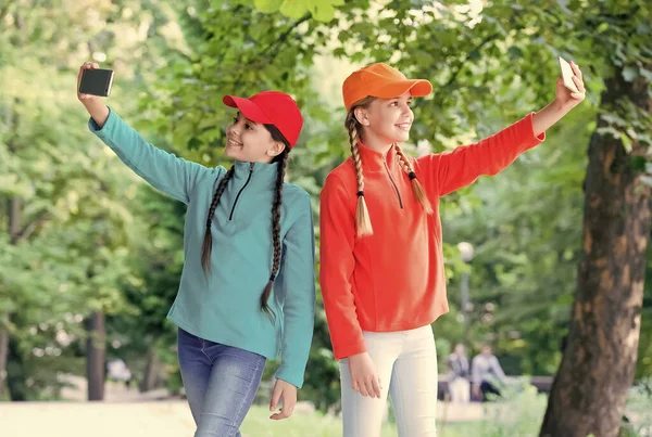 Šťastné holčičky, aby video hovor s moderními mobilními telefony v parku, videokonference — Stock fotografie