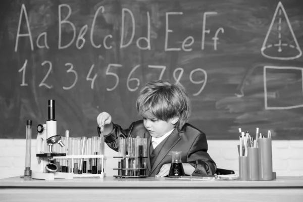 Kleiner Junge mit Mikroskop in der Schulstunde. Kleiner Junge studiert Chemie. Lernen für die Zukunft. Biologie. Überprüfen Sie die Ergebnisse. Medizinisches Konzept. Kleines Geniekind. Reagenzgläser mit Flüssigkeit für die Forschung — Stockfoto
