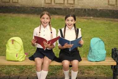 İlginç bir şey öğrendim. Kitapçığı tutan genç öğrencilere sürpriz oldu. İlkokulda eğitim. Okul kızları konuyu birlikte öğreniyor. Ders çalışırken iyi eğlenceler. Okul üniformalı mutlu kızlar.