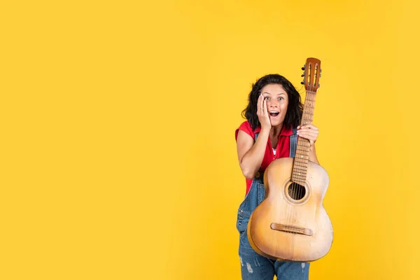 Hipster féminine souriante avec des vêtements à la mode jouant de la guitare, de l'espace de copie, de la musique country — Photo