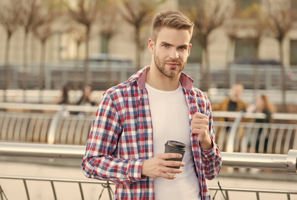 businessman walking outdoor. smart casual dressed person drinking coffee mug outdoor. Caucasian male resting in street on the way to work. Young man in checkered shirt. Enjoying beautiful morning