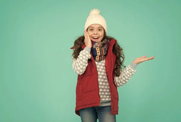 Şaşırmış kıvırcık saçlı bir genç kız Noel tatilinde kabarık yelek giyer ve örgü örer. Ürün sunar, fotokopi alanı, kış alışverişi — Stok fotoğraf