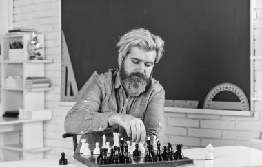 Zihin savaşı. Satranç yarışması için sakallı adam eğitimi. Tahta üzerinde satranç figürleri. Odaklanmış öğretmen. Rakip satranç taşlarına saldırmayı ve onları yakalamayı düşünüyor. Bir sonraki hamleyi düşünüyorum.