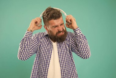Sakallı ve bıyıklı beyaz adam dijital kulaklıkla yüksek sesli müzik dinlemeyi sevmez.