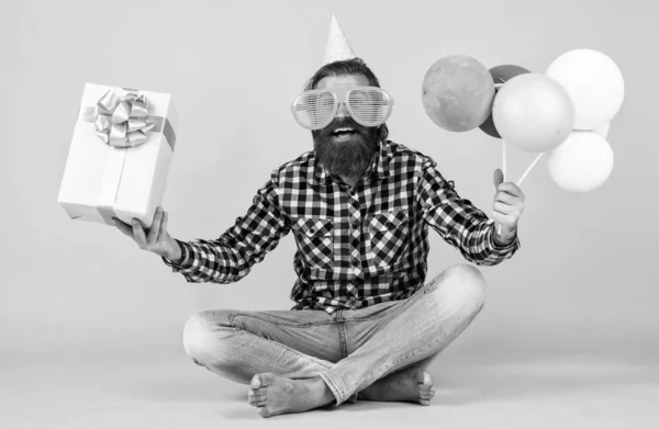Komik, vahşi, sakallı, kareli gömlek giyen, sakallı, bıyıklı parti balonları ve hediye kutusu olan bir adam. — Stok fotoğraf